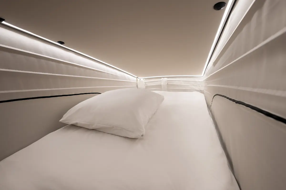 Спальне місце кемпера Mercedes Marco Polo з білою постіллю та LED-підсвічуванням.