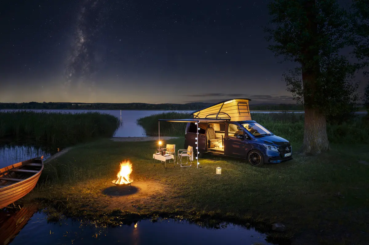 Mercedes Marco Polo V-клас кемпер вночі біля озера з вогнищем.